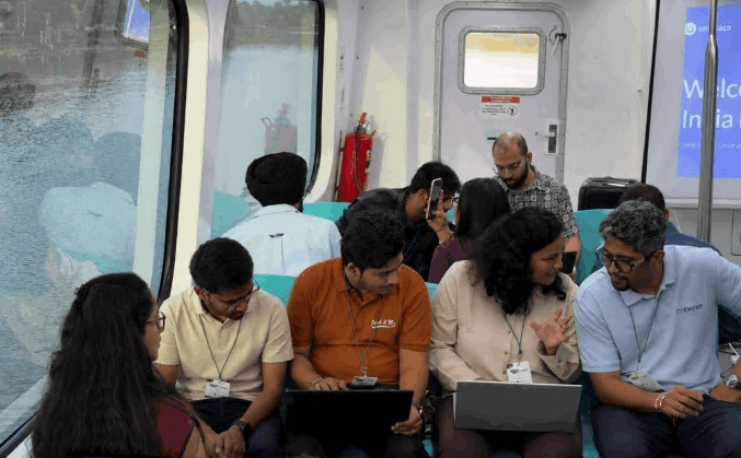 Team aboard the Kochi Water Metro, city/backwaters in the background