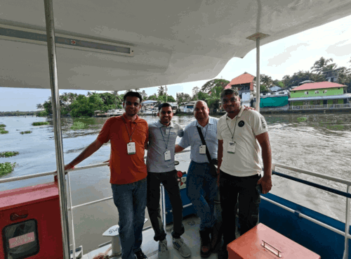 Team aboard the Kochi Water Metro, city/backwaters in the background
